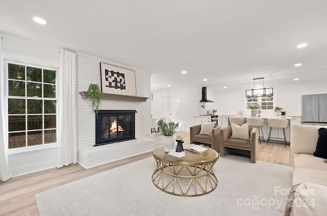 living room featuring light hardwood / wood-style flooring and a brick fireplace