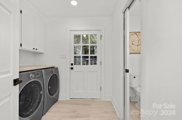 laundry room with cabinets, light wood-type flooring, and washing machine and clothes dryer