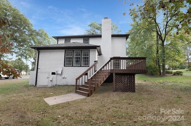 rear view of property featuring a wooden deck and a yard