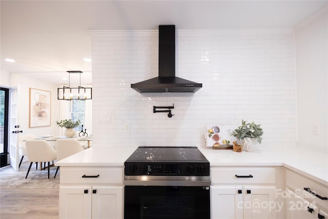 kitchen featuring wall chimney range hood, crown molding, stainless steel electric range, light wood-type flooring, and white cabinetry