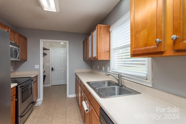 kitchen with sink, stainless steel appliances, a textured ceiling, and light tile patterned floors