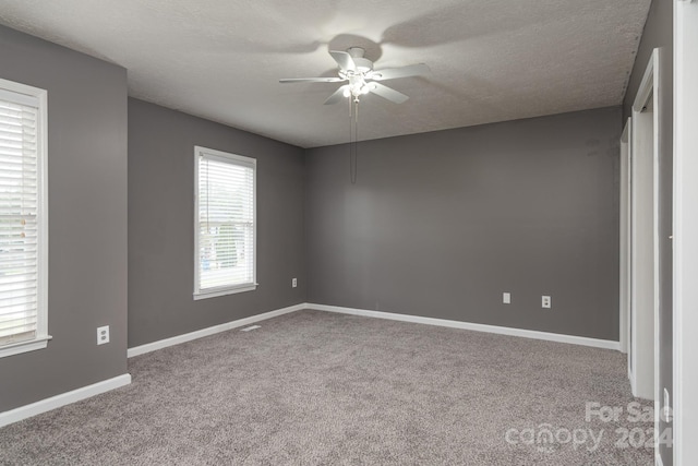 carpeted spare room with a textured ceiling and ceiling fan