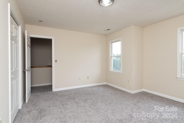 unfurnished bedroom featuring a textured ceiling and light colored carpet