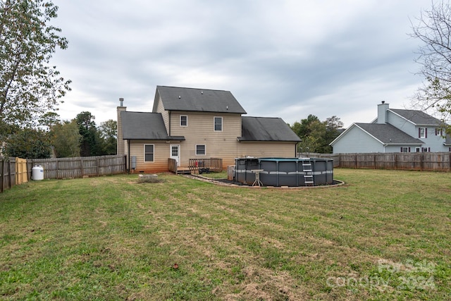 rear view of property with a fenced in pool and a lawn