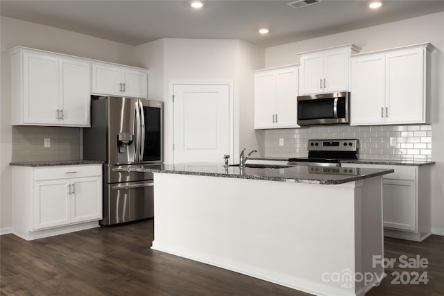 kitchen with an island with sink, backsplash, white cabinetry, appliances with stainless steel finishes, and dark hardwood / wood-style flooring