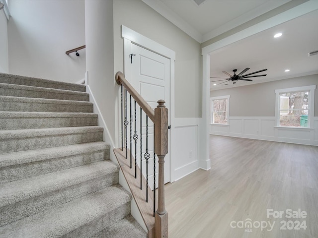 stairs with ceiling fan, hardwood / wood-style floors, and crown molding