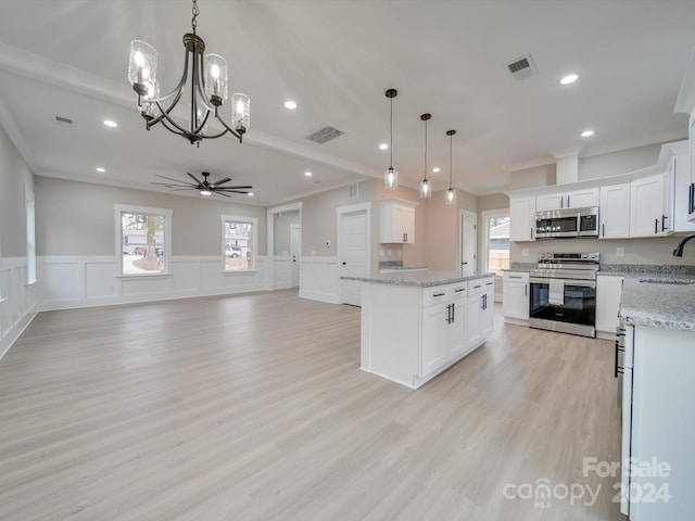 kitchen with pendant lighting, ceiling fan with notable chandelier, a kitchen island, white cabinetry, and stainless steel appliances