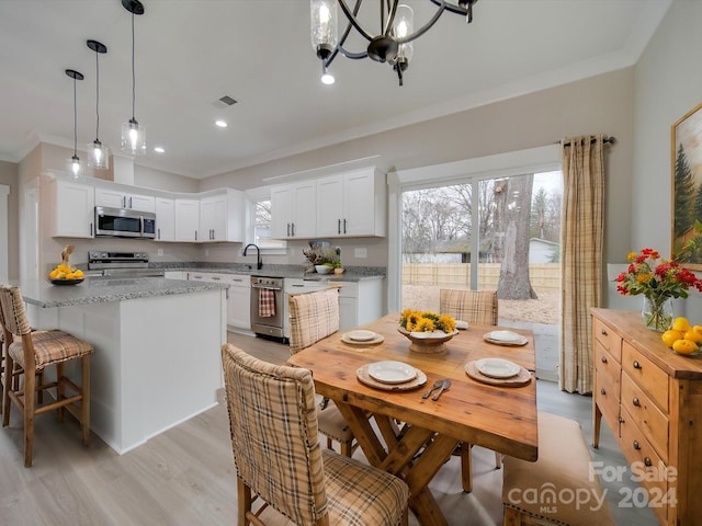 kitchen with crown molding, light wood-type flooring, appliances with stainless steel finishes, decorative light fixtures, and white cabinetry