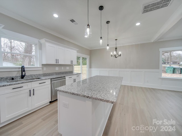 kitchen featuring stainless steel dishwasher, a kitchen island, sink, decorative light fixtures, and white cabinetry