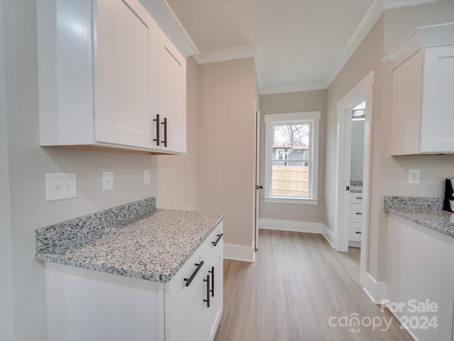 kitchen featuring white cabinets, light wood-type flooring, light stone countertops, and ornamental molding