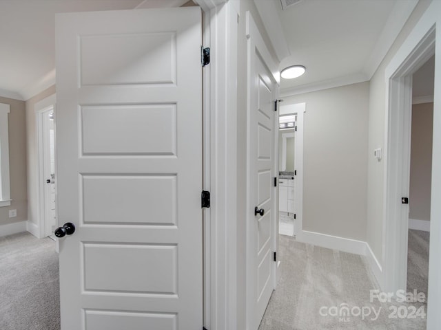 hallway with ornamental molding and light carpet