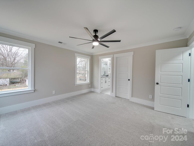 unfurnished bedroom featuring ensuite bath, ceiling fan, light colored carpet, and ornamental molding