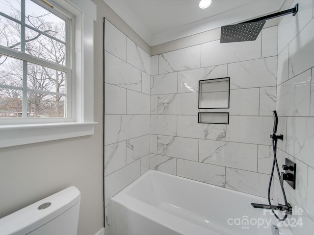 bathroom with tiled shower / bath, toilet, and plenty of natural light