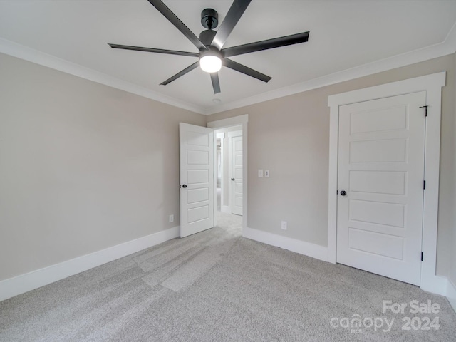 empty room featuring ceiling fan, light colored carpet, and crown molding