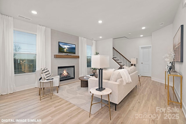 living area featuring light wood-style flooring, a fireplace, visible vents, and recessed lighting