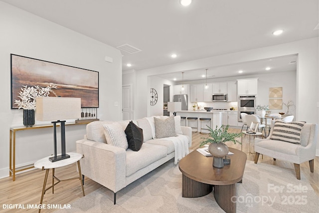 living area featuring light wood finished floors, baseboards, visible vents, and recessed lighting