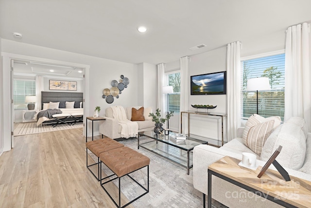 living area with light wood-style flooring, visible vents, and recessed lighting