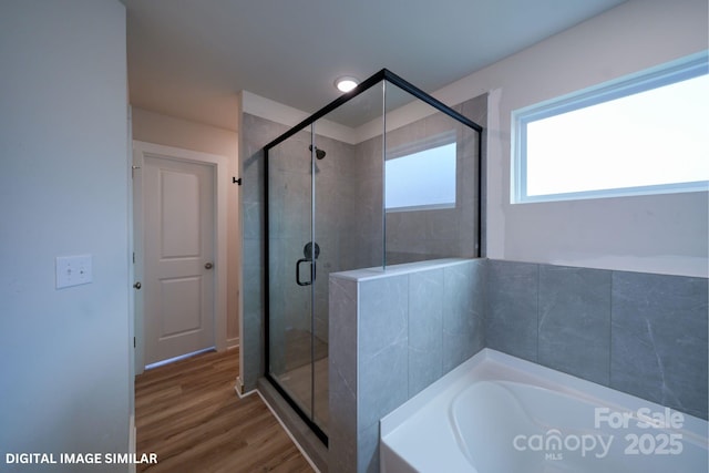 full bathroom with a stall shower, a bath, and wood finished floors