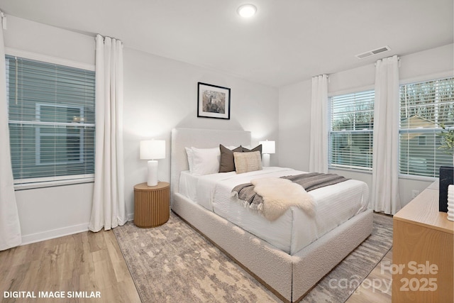 bedroom featuring baseboards, visible vents, and wood finished floors