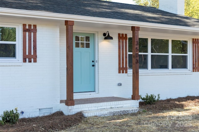 doorway to property featuring crawl space, a shingled roof, and brick siding