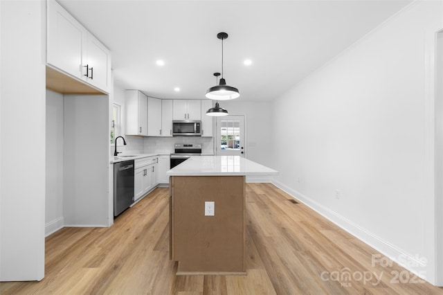 kitchen featuring a sink, a center island, stainless steel appliances, light countertops, and decorative backsplash