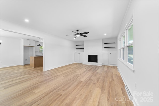 unfurnished living room featuring a ceiling fan, a fireplace, light wood-type flooring, and baseboards