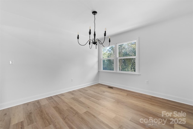 unfurnished dining area featuring a notable chandelier, visible vents, light wood-style flooring, and baseboards