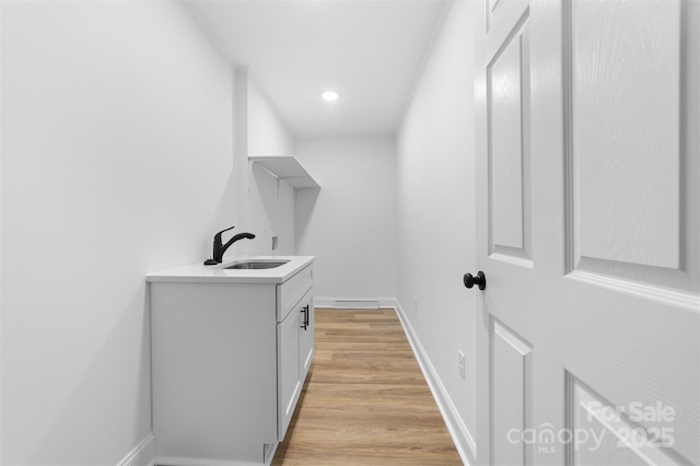 washroom featuring a sink, light wood-type flooring, baseboards, and recessed lighting