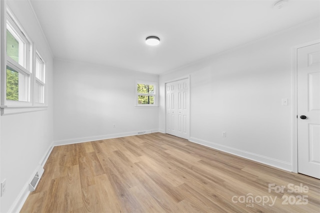 spare room featuring crown molding, light wood-style flooring, baseboards, and visible vents