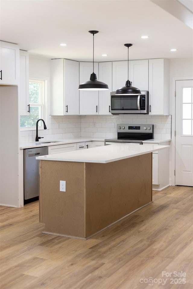 kitchen featuring a center island, white cabinetry, stainless steel appliances, and a sink