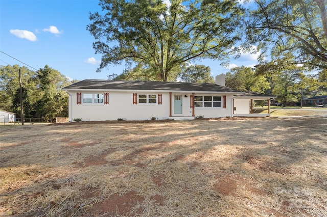 ranch-style house featuring an attached carport and a chimney