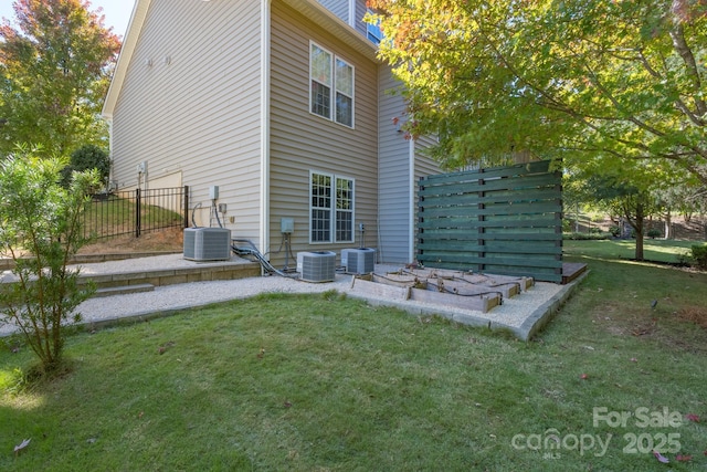 rear view of house with central AC and a lawn