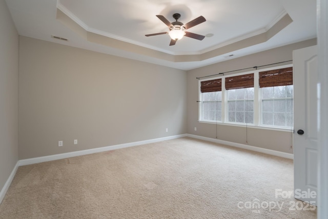 spare room featuring ceiling fan, light colored carpet, ornamental molding, and a raised ceiling