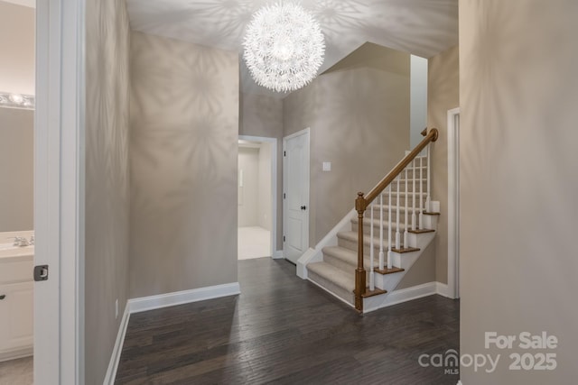 staircase featuring hardwood / wood-style flooring, sink, and a chandelier