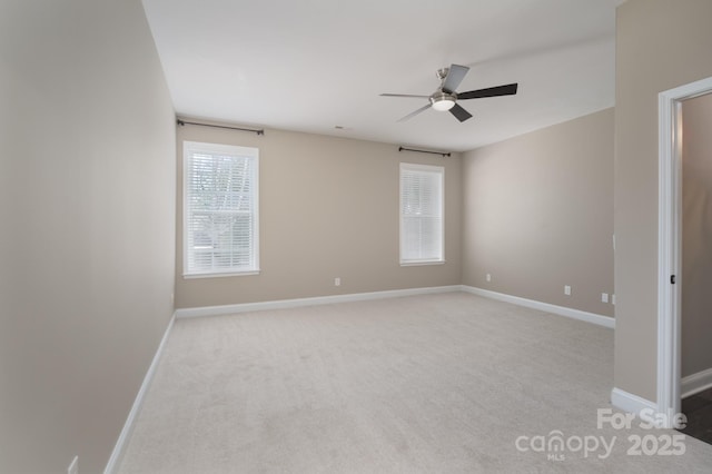 carpeted empty room with ceiling fan and a wealth of natural light