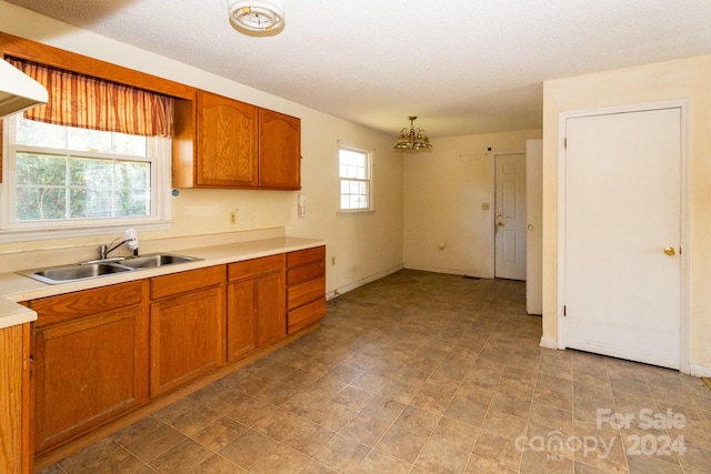 kitchen featuring a textured ceiling, pendant lighting, sink, and a chandelier