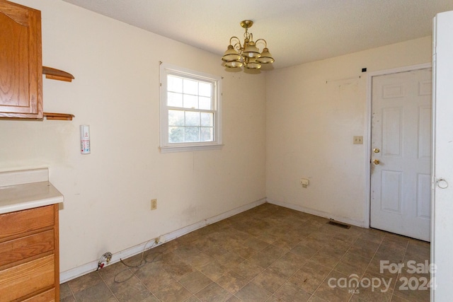 unfurnished dining area featuring a notable chandelier