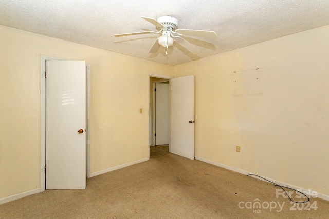 spare room featuring a textured ceiling, light carpet, and ceiling fan