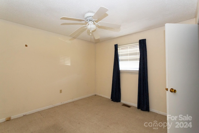 carpeted empty room featuring a textured ceiling and ceiling fan