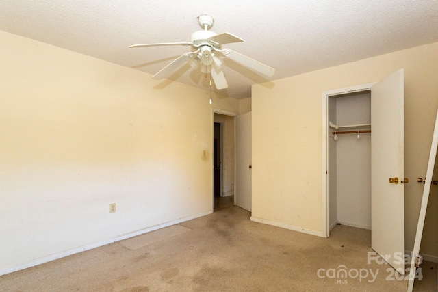 unfurnished bedroom featuring a closet, a textured ceiling, light colored carpet, and ceiling fan