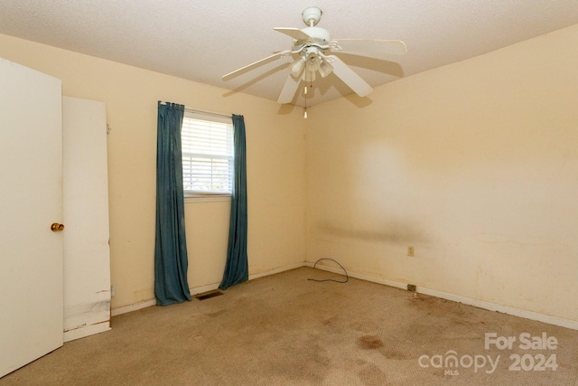 spare room featuring ceiling fan, a textured ceiling, and light carpet