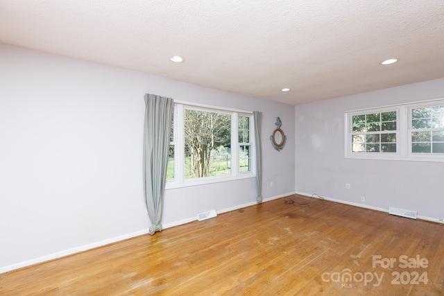 unfurnished room featuring a textured ceiling and light hardwood / wood-style flooring