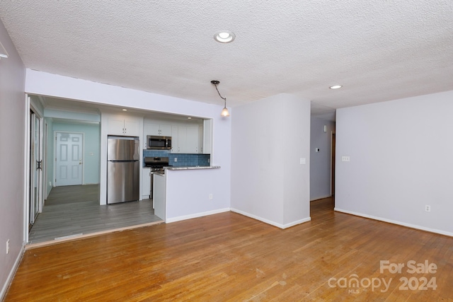 unfurnished living room featuring light hardwood / wood-style floors and a textured ceiling