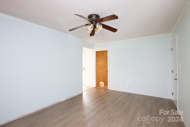 empty room with ceiling fan, hardwood / wood-style flooring, a textured ceiling, and ornamental molding