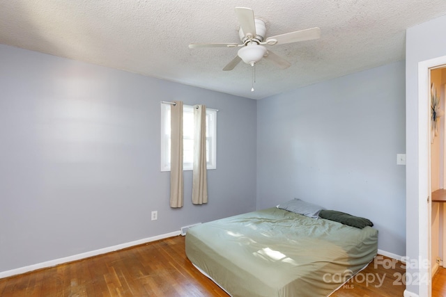 bedroom with hardwood / wood-style floors, a textured ceiling, and ceiling fan