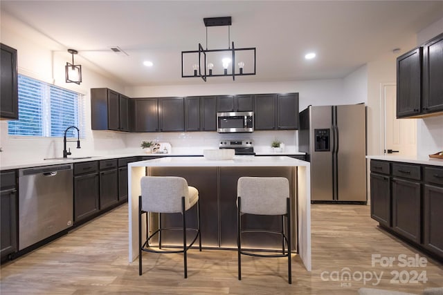 kitchen featuring sink, appliances with stainless steel finishes, decorative light fixtures, and a kitchen island