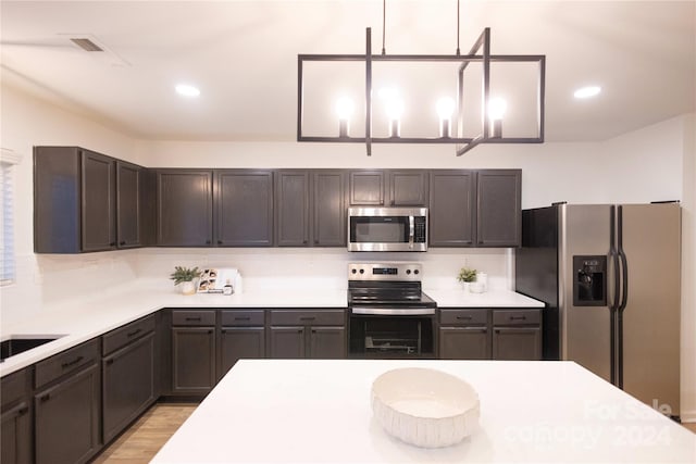 kitchen featuring dark brown cabinets, tasteful backsplash, appliances with stainless steel finishes, and light wood-type flooring