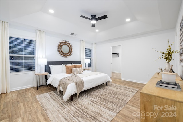 bedroom featuring a tray ceiling, light wood-type flooring, and ceiling fan