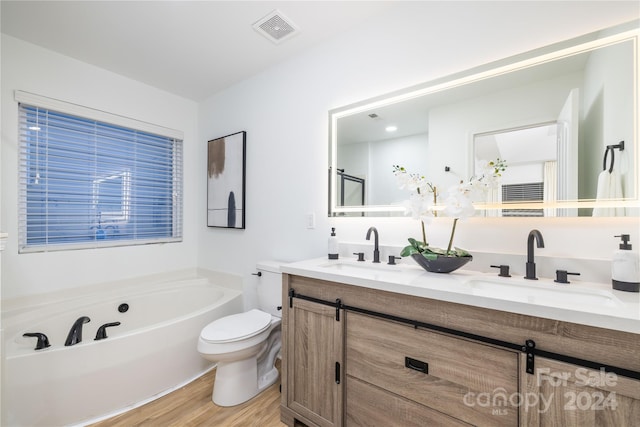 bathroom featuring hardwood / wood-style floors, vanity, a tub, and toilet