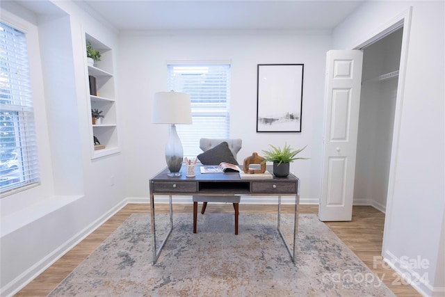 office area with crown molding, built in features, and wood-type flooring